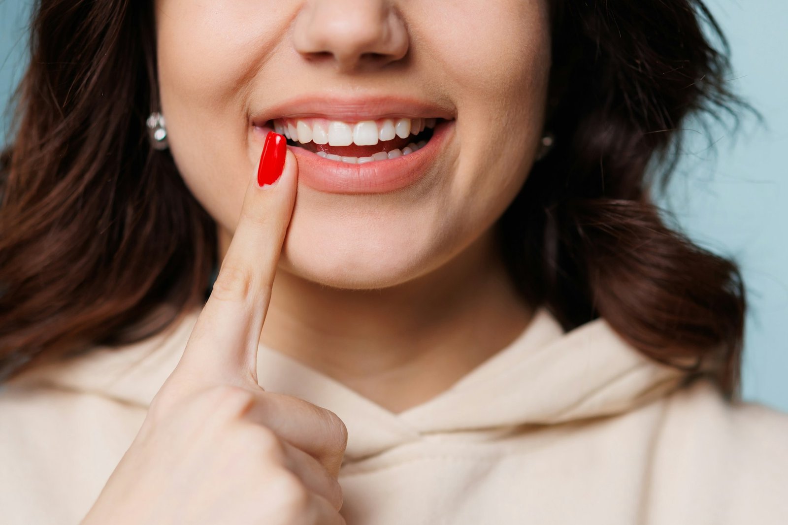 Happy girl showing toothy smile, pointing finger at healthy white teeth. Clinic patient satisfied